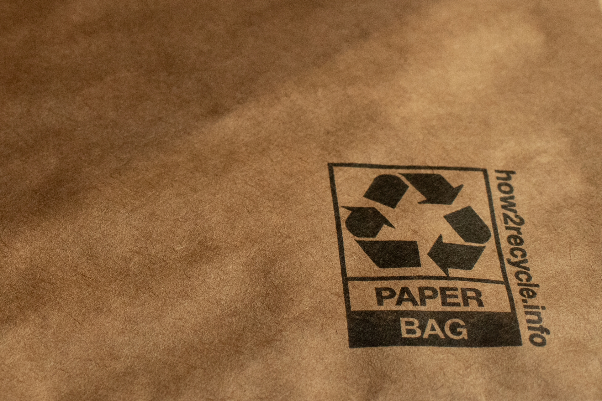 Detail of a padded mailer showing a recycling symbol, the words "paper bag," and a website: how2recycle.info