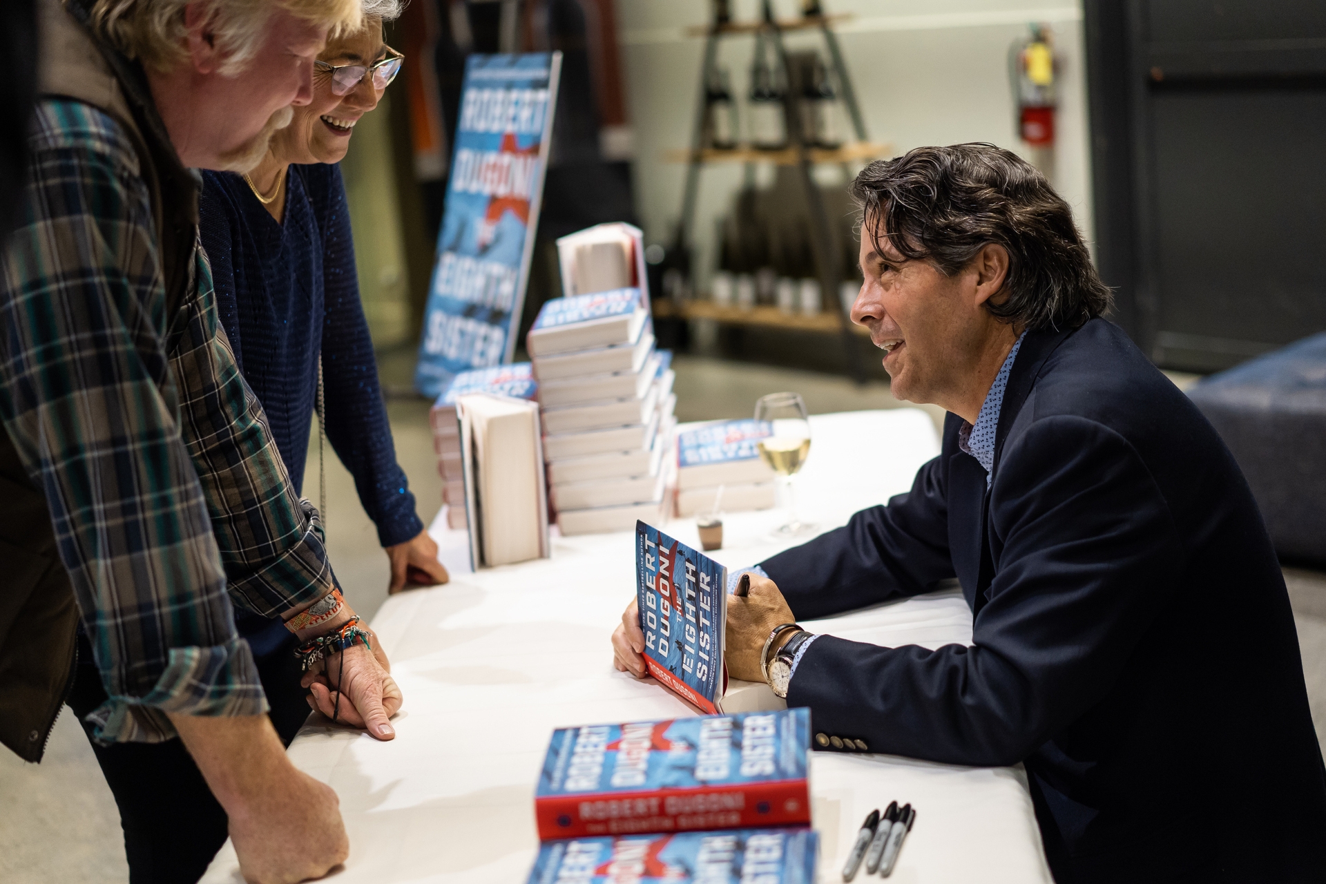 Author Robert Dugoni signs a copy of his book for a fan, looking up at the fan and engaging in conversation.