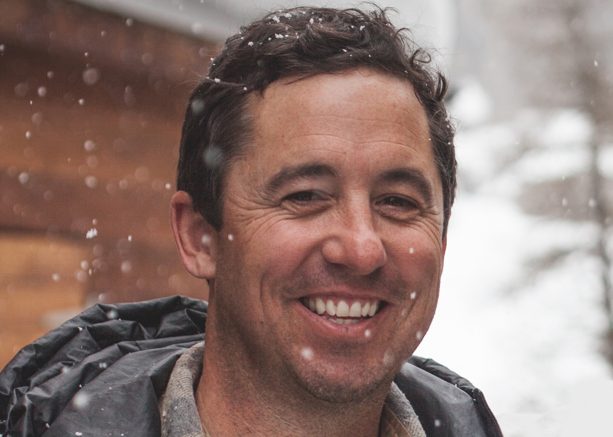 Porter Fox, the Amazon author profiled in this story, is smiling into the camera with falling snow in the background.