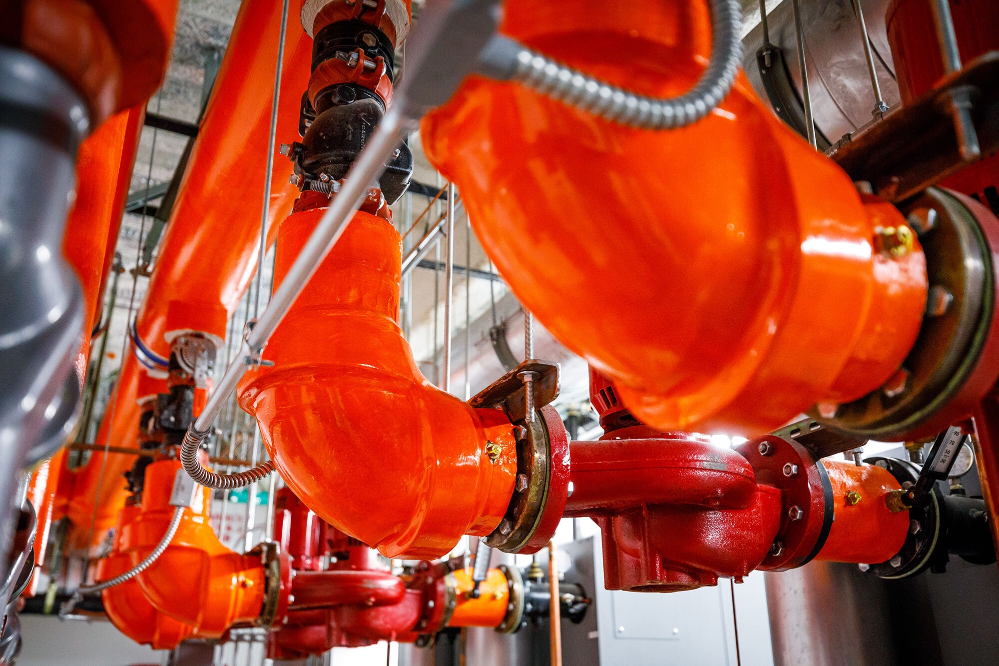 Three bright orange steam pipes are seen in a mechanical room under the Westin Seattle.