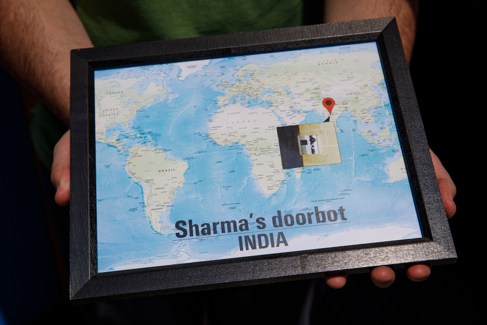 A framed map with a photo of a door showing an early Ring customer, Sharma in India.
