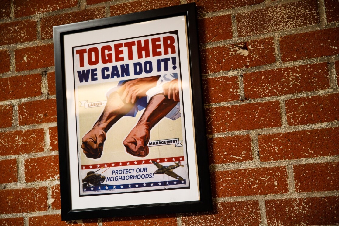 A poster on a wall at Ring headquarters showing clenched fists and rolled up sleeves. The slogan says 'Together We Can Do It! Protect Our Neighbors'.
